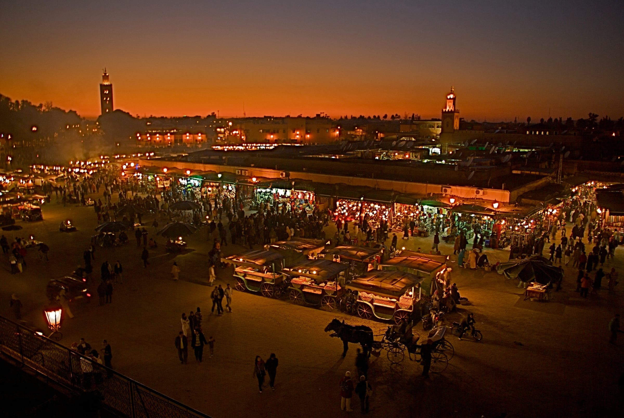 Jemaa el-Fna à la nuit tombée, minaret de la Koutoubia au fond